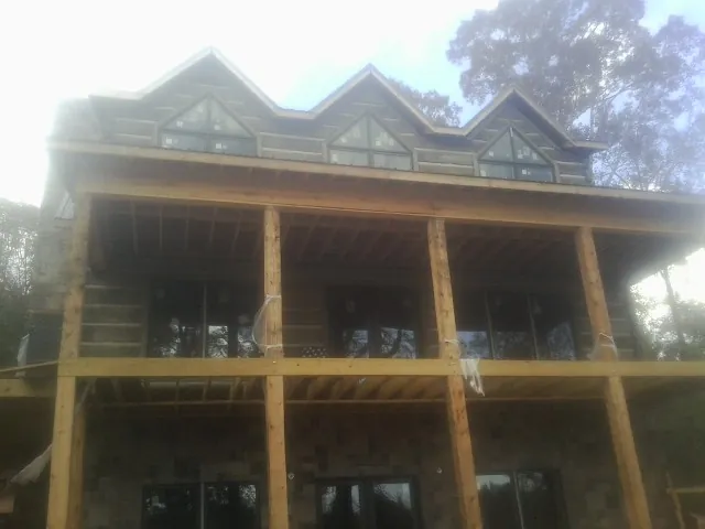 Dormers and porch framing on a large log home under construction — Roof Coating work by our crew in Hammond