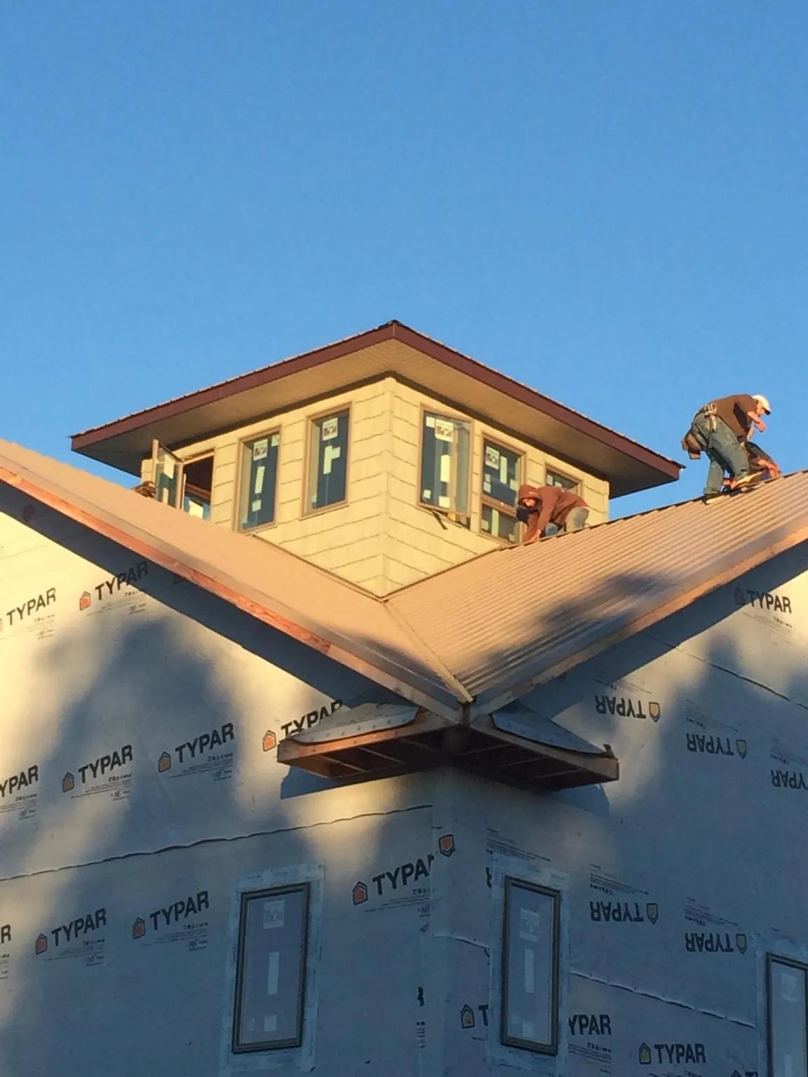 Roofers working around a rooftop cupola on a new metal roof at sunset — Roof Waterproofing in Hammond by Roofing Brothers
